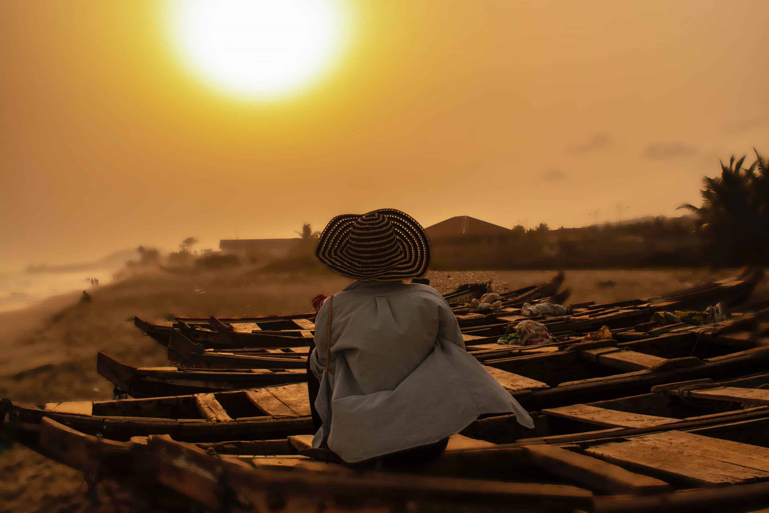 Person sitting on a boat in the sand in Ghana