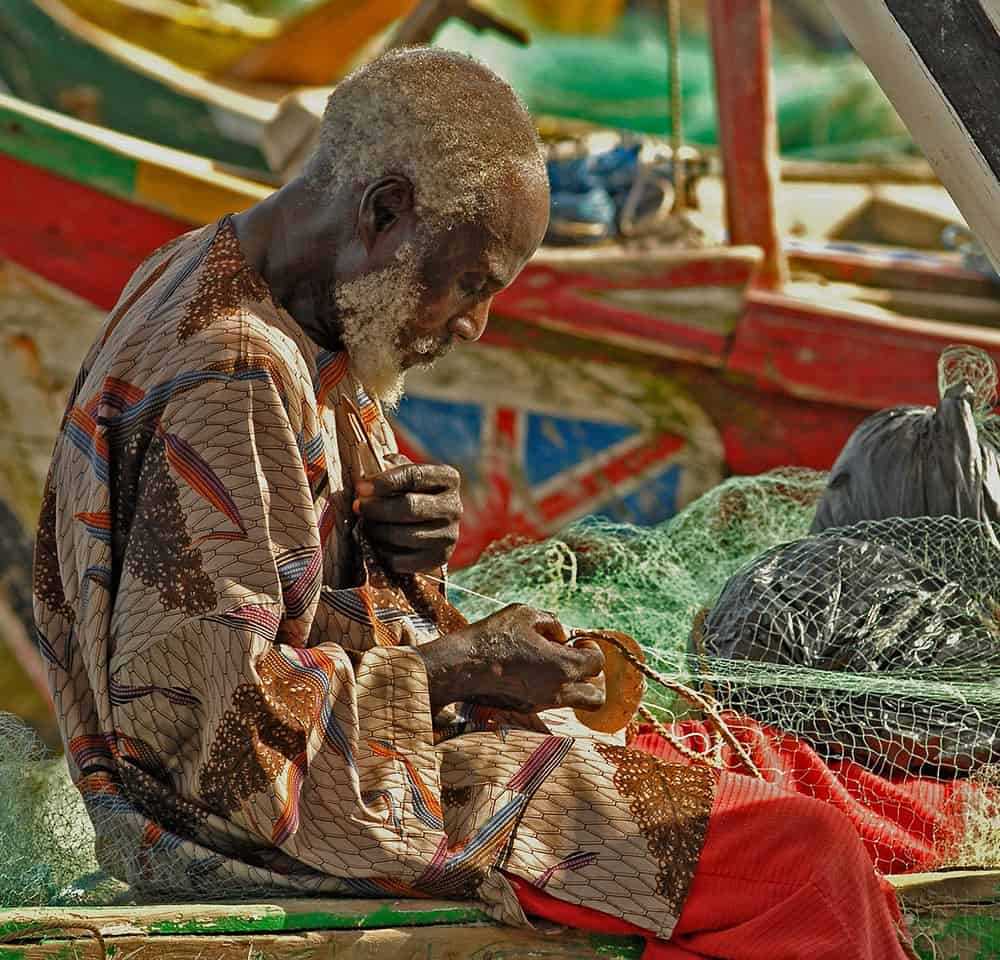 Old man handling fishing nets in a boat in Ghana